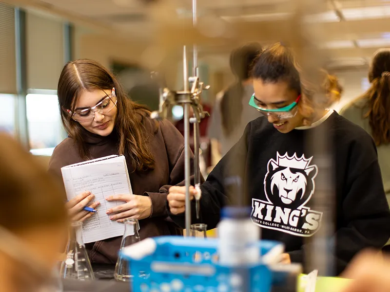 two students wearing protective gear in a lab