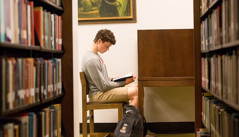 student reading a book in the library