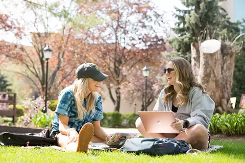 students sitting outdoors on the campus lawn