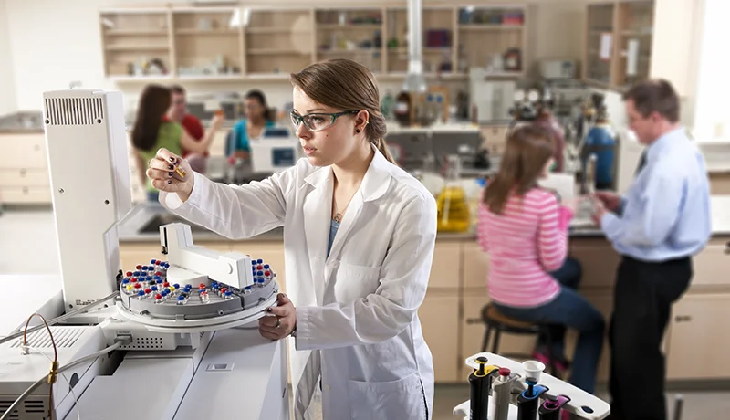 student in lab coat looking at test tube