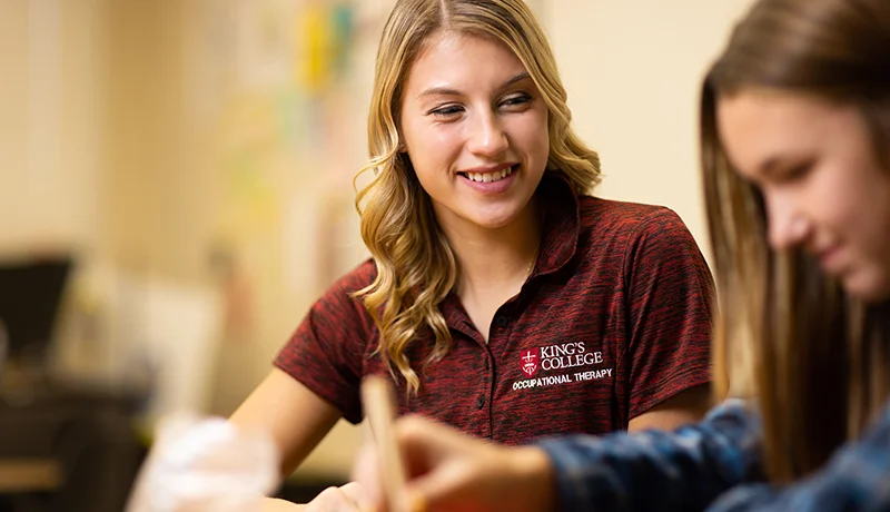 Occupational therapy student working with a girl in a classroom setting