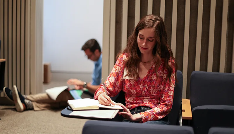professional writing student studying for writing degree in a library