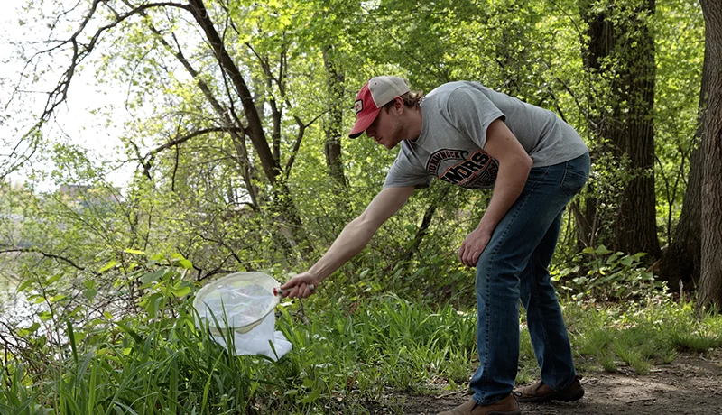 student collecting refuse outdoors