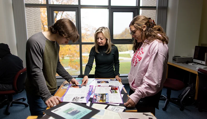 communications degree students and a professor looking at marketing materials
