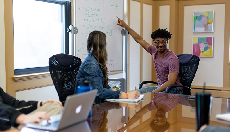 student pointing at a whiteboard