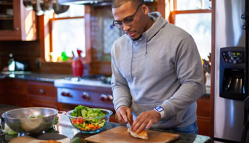 A student chops up vegetables in the kitchen