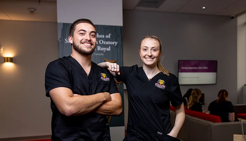 two occupational therapy degree students in polos posing in a medical facility