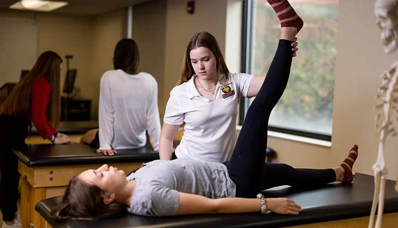 student lifting a patient's leg