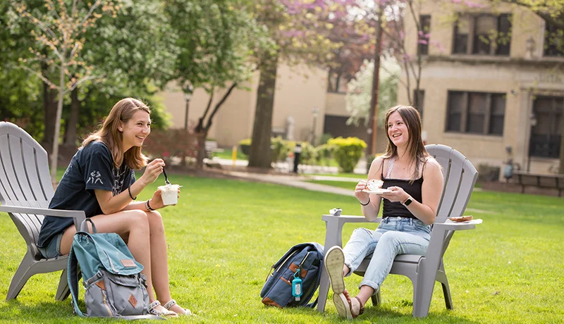 two psychology major students in Adirondack chairs outdoors