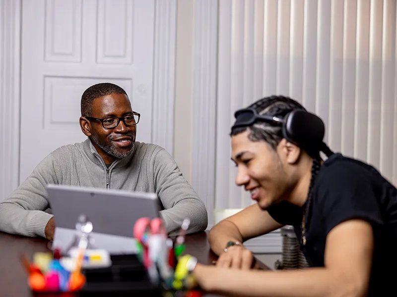 a student working with a staff member at a round table