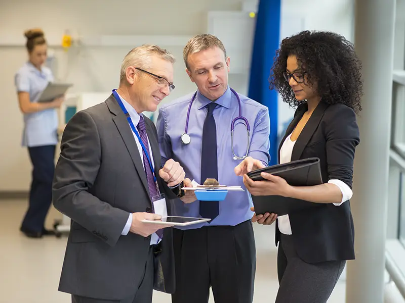 three healthcare executives meeting in a clinical environment