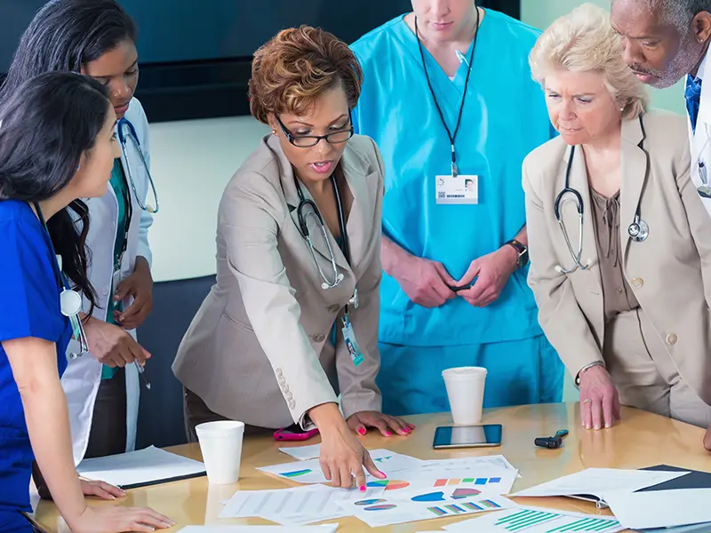 several nursing executives reviewing printed charts in a conference room