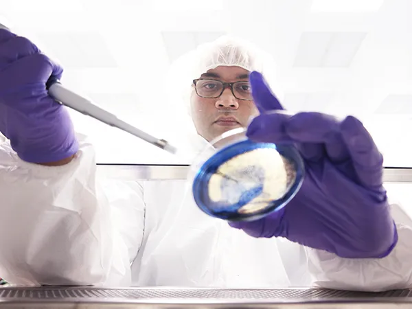 student in protective wear using syringe and beaker
