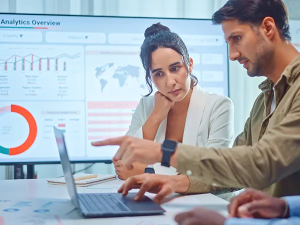two people discussing a chart on a laptop