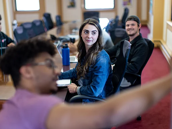 2 economics major students watching another present a project