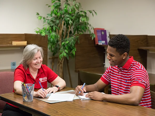 professional writing student writing an essay with the help of a professor