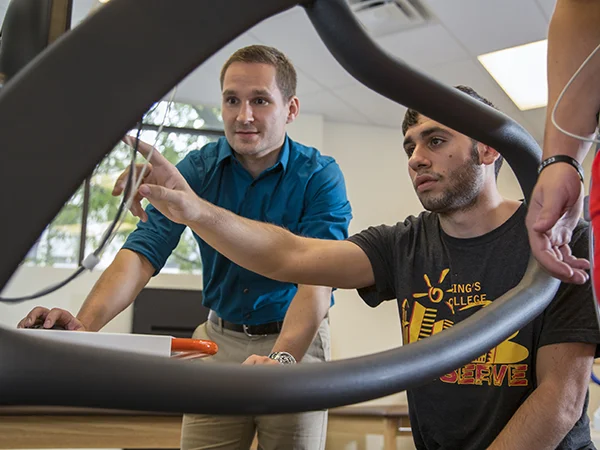 student and professor pointing at a computer monitor