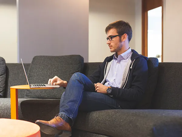 student sitting in a lounge area using a laptop