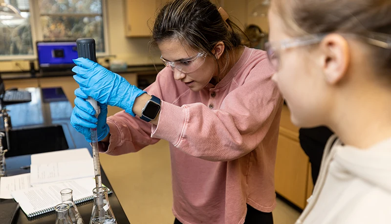 environmental chemistry students filling a beaker in a lab