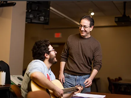 a guitar player sitting with his instructor