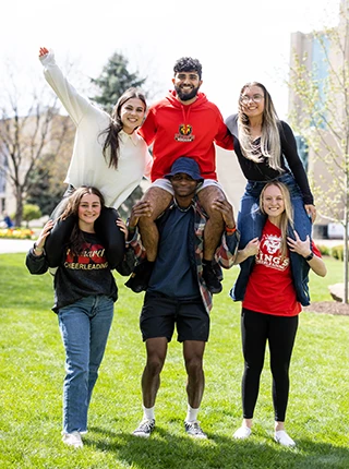 students stand outside with other students on shoulders