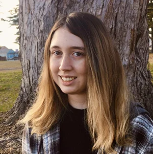 Madysen posing for a portrait in front of a large tree.