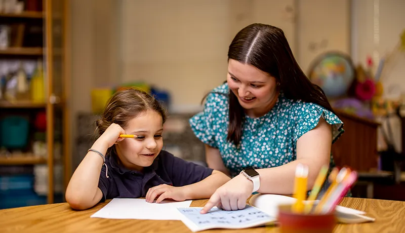 a teacher helping a student at a desk