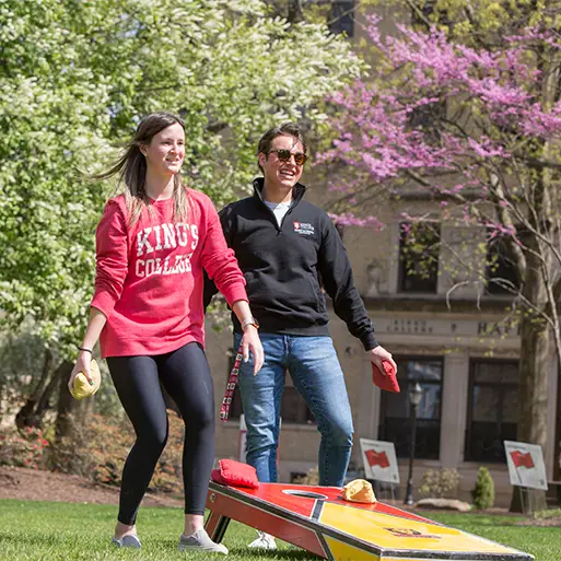 students outdoors playing cornhole