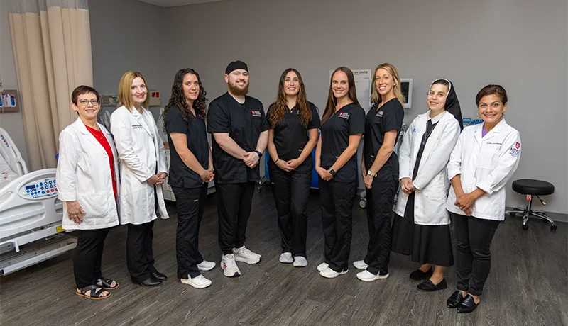 nursing school graduates pose for a group photo in scrubs
