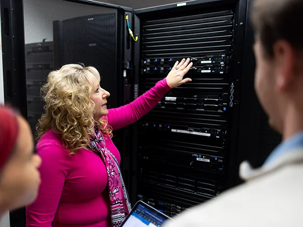 professor instructing students in front of a server