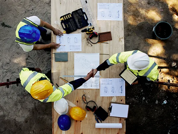 construction managers shaking hands at a drafting table