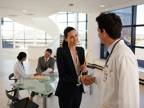 bachelor of healthcare management graduate shaking a doctor's hand