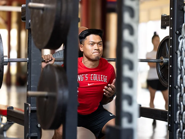 student performing a squat in the gym