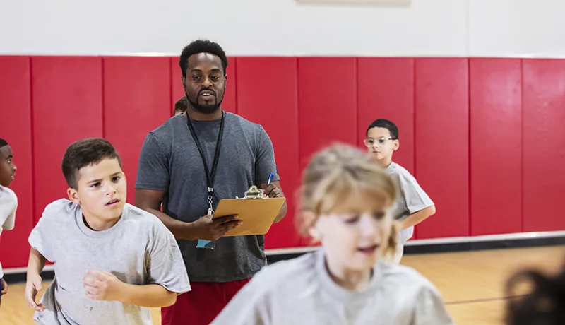 a gym teacher supervising childrens' sports