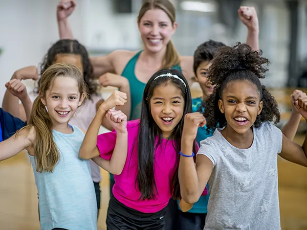 students flexing their biceps in the gymnasium