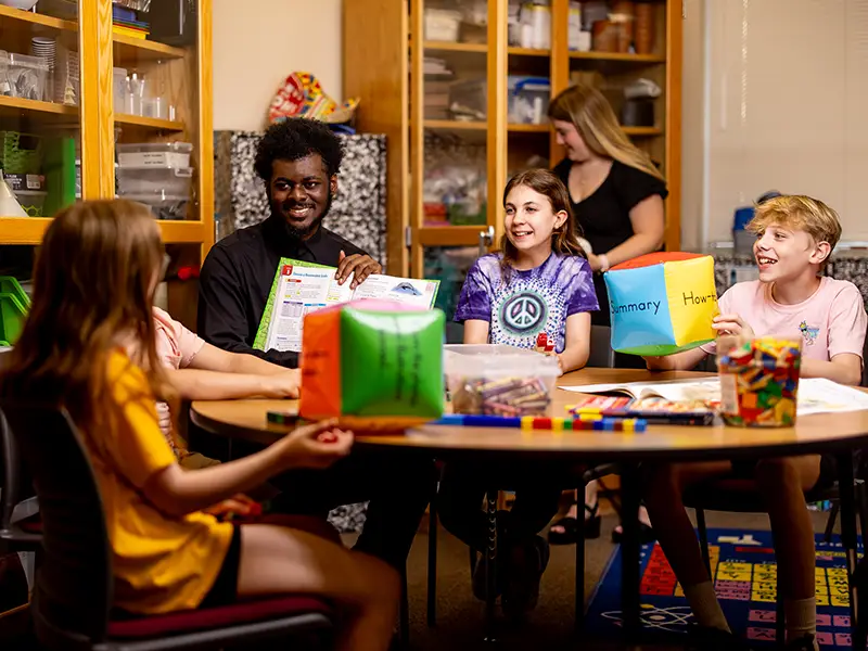 a teacher showing a book to adolescents in a classroom