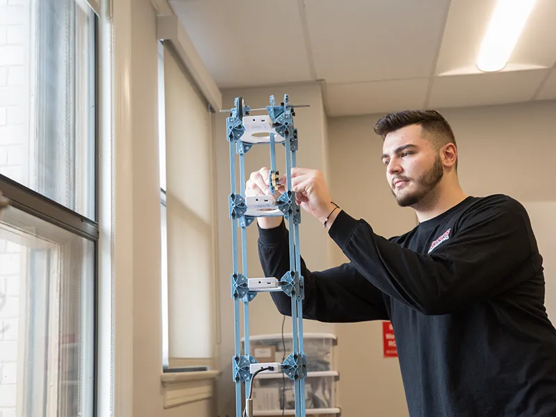 student standing and operating a machine