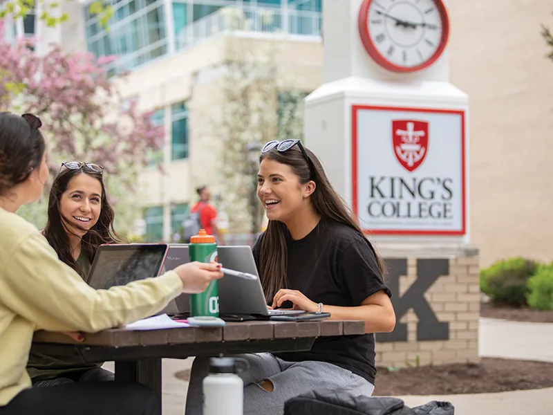 students talking outside at a picnic table