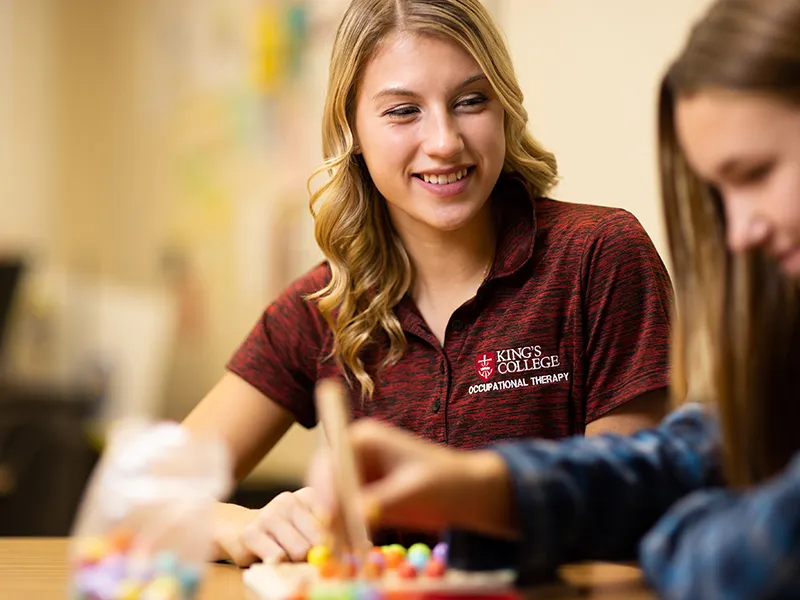 student in a Polo shirt smiling at another student