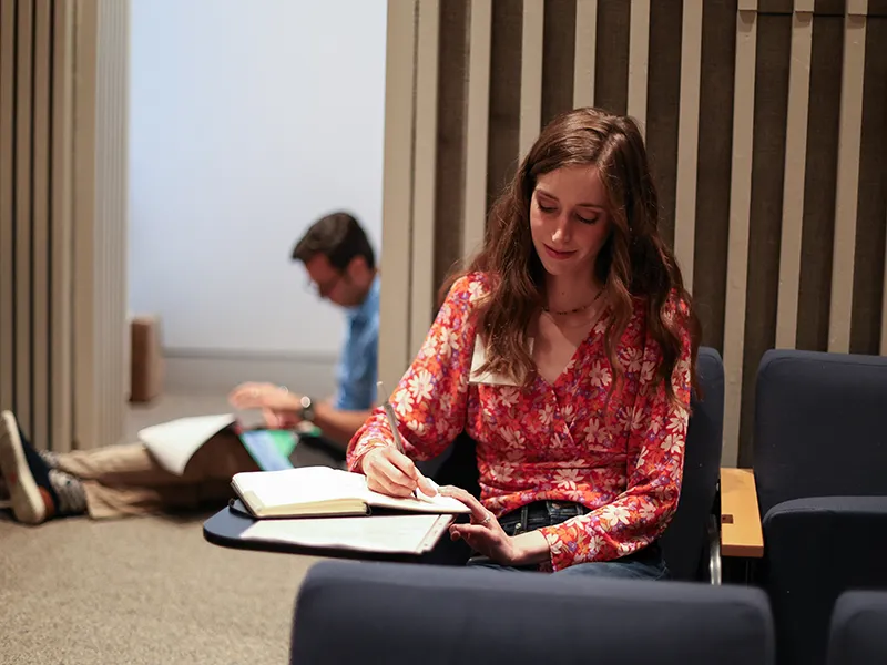 student studying from a textbook in a library setting