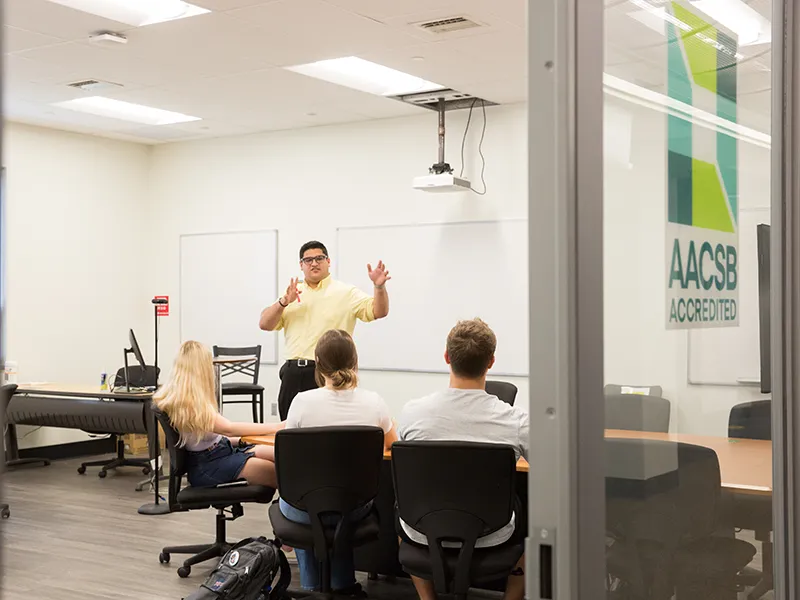 a student gives a presentation in front of a whiteboard