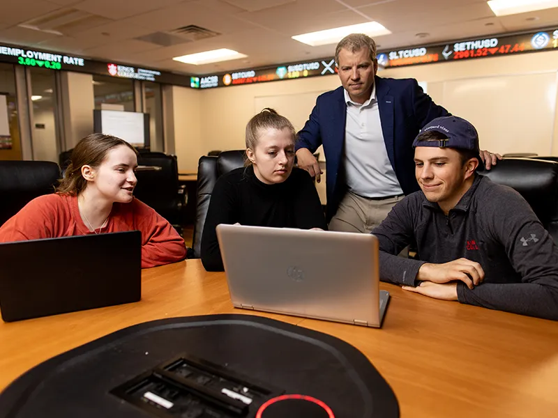 Professor and students reviewing content on a laptop