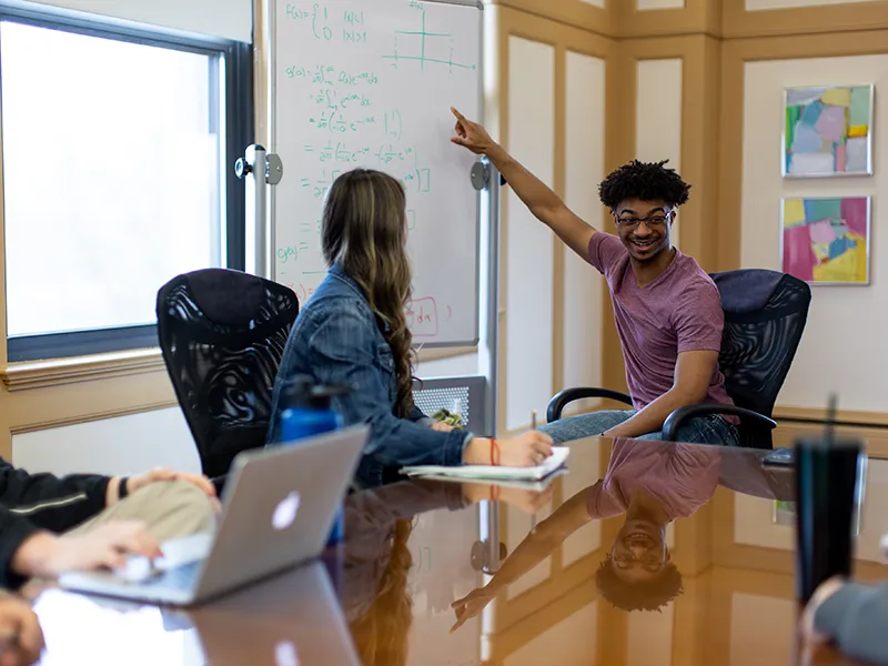 student pointing at a whiteboard