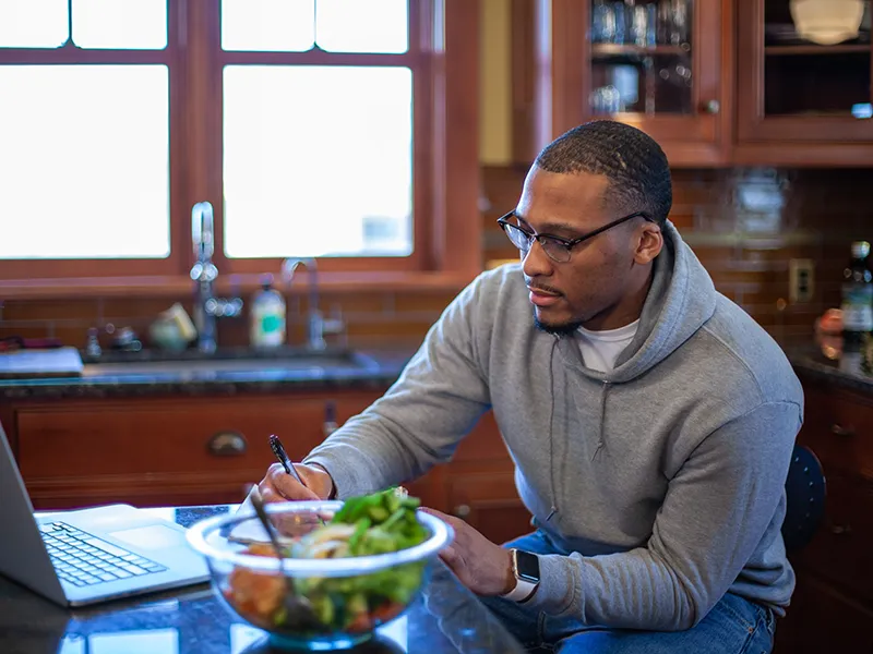 person sitting in the kitchen with a salad