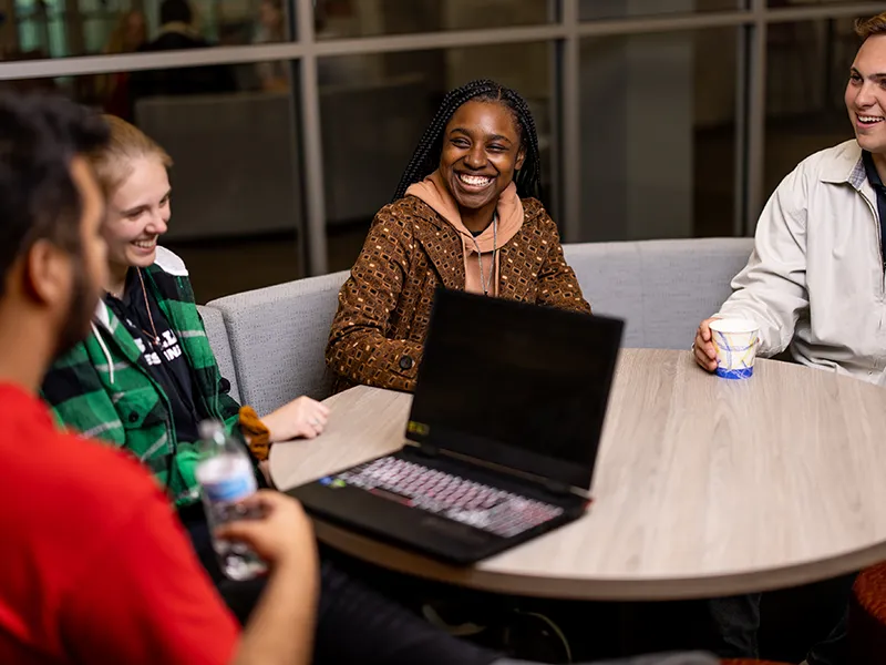 Students meeting at a table with laptop