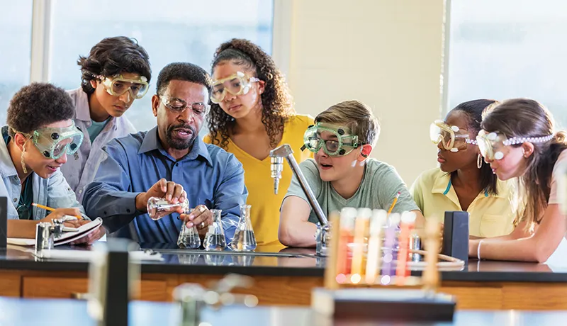 students in protective equipment in a science classroom