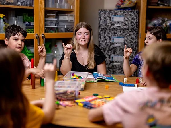 a teacher in a classroom table with a group of children