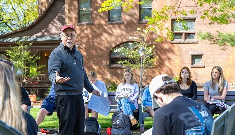 Theology degree professor lecturing students outdoors