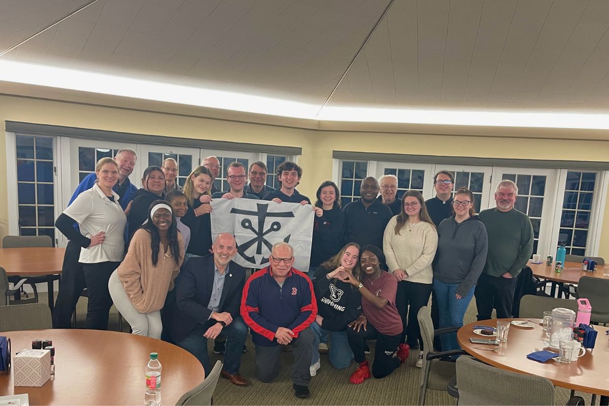 Group photo of volunteers holding up the Congregation Holy Cross Symbol