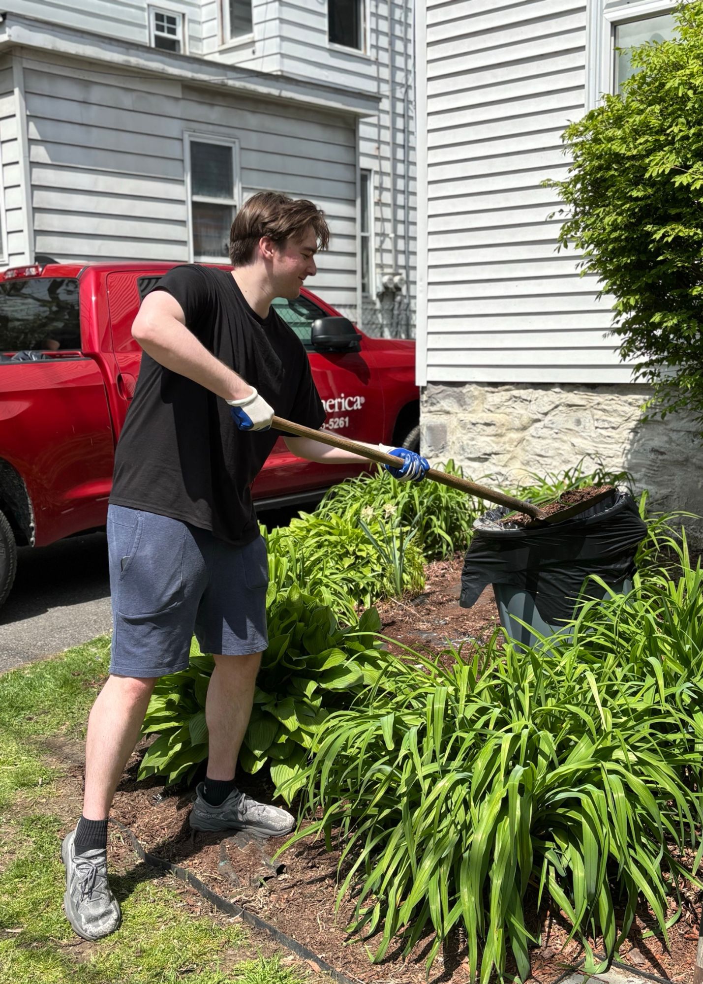 Student volunteer shoveling mulch at the VOA site.